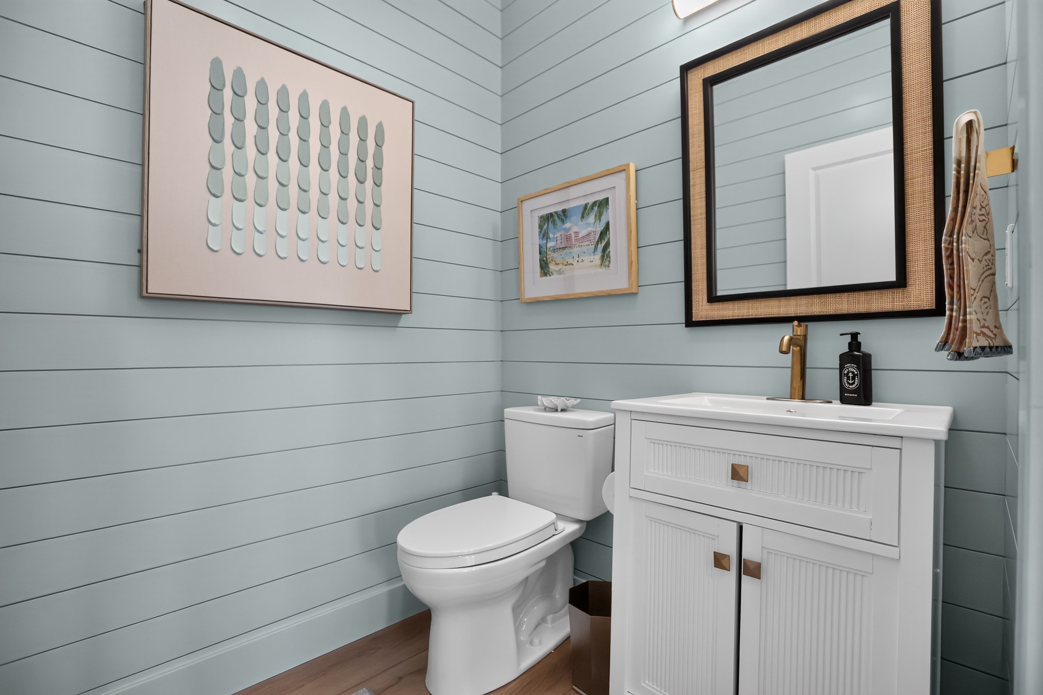 Coastal powder room with light blue shiplap walls and gold fixtures